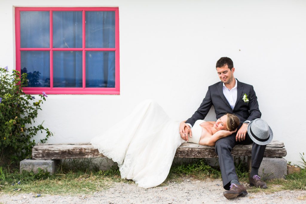 Couple de mariés sur un banc à Biarritz au Pays Basque. Photographe de mariage moderne et primé.